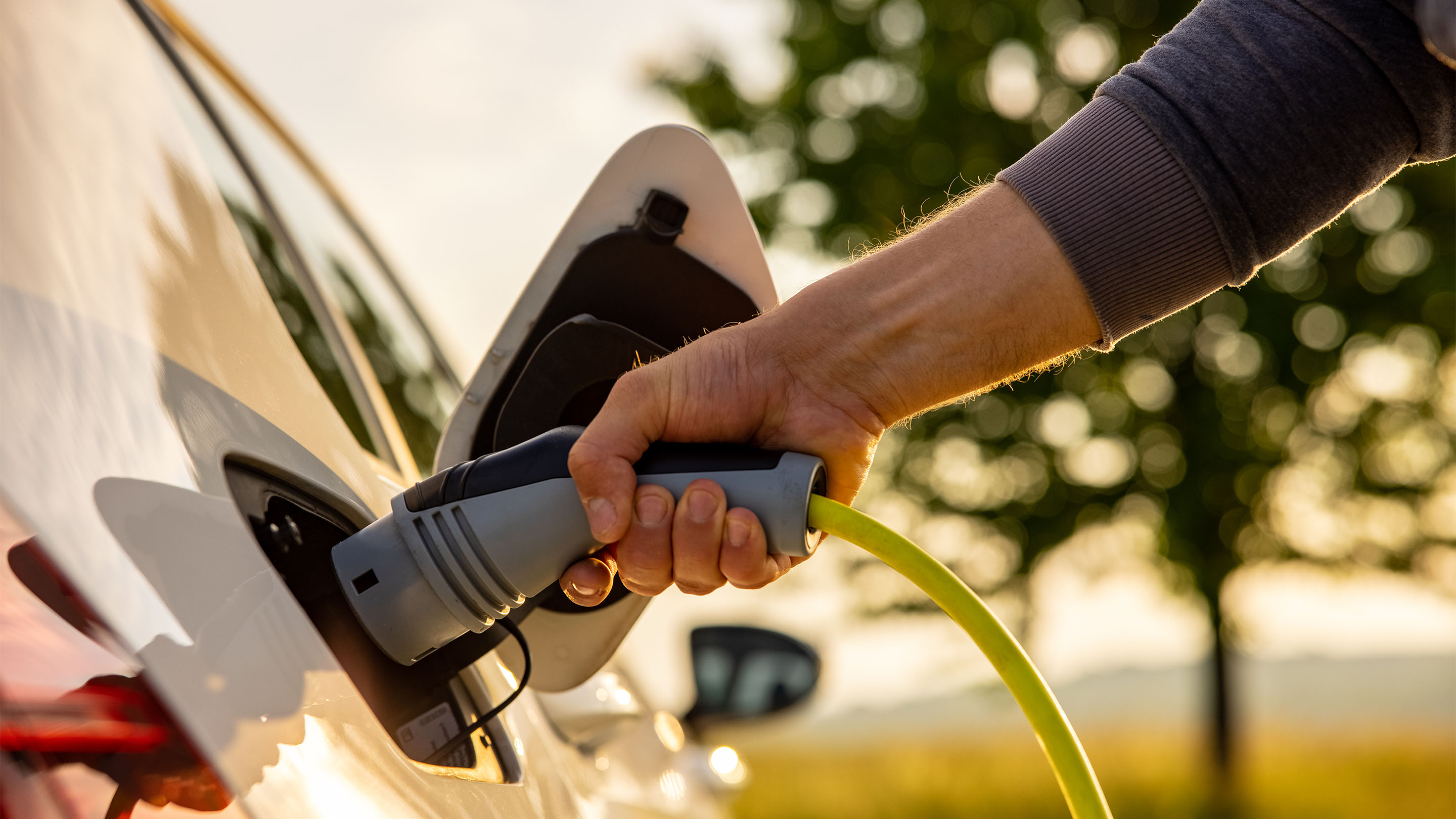 Person plugging a power cord into an electric car